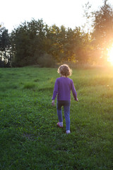 Little girl running on meadow with sunset