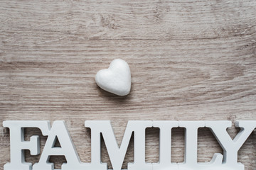 Abstraction on the theme of the family. Heart and a white inscription family of wood on a wooden background.