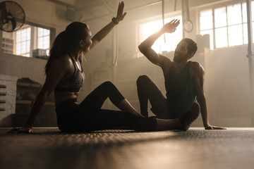 Man and woman giving high five in gym - obrazy, fototapety, plakaty