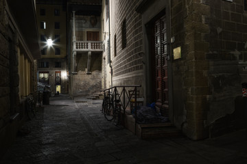 Fototapeta na wymiar The homeless man sleeps on the porch, hiding behind a blanket. Florence, Italy.