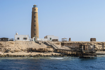 A scenic view of a seashore with an old picturesque lighthouse open for visitors, and a long,...