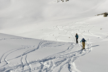 Background: man and woman, sporty, walking with snowshoes in fresh snow, high mountains, sunny and cold day, following path, head towards peak, rock, winter, shadow, Alps, Valais, Simplon Pass, Swiss