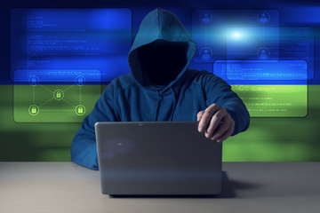 Hacker sitting in front of a laptop on background of digital flag of Ukraine. Cyber Security concept.