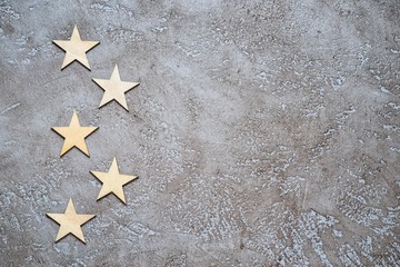 five wooden hearts lie zigzag in the form of bullets on the left of a textured neutral cement...