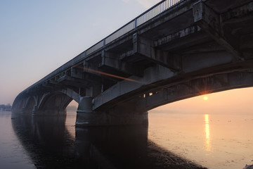 Picturesque view over the Metro (Subway) Bridge over the Dnipro river in Kyiv, Ukraine. Sunrise at winter morning