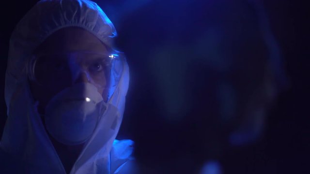 Criminal in lab costume cleaning fingerprints from glass, dishonest police