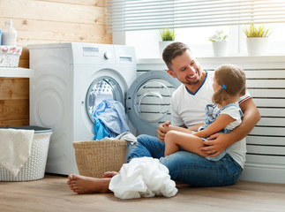 Happy family man father householder and child   in laundry with washing machine
