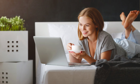 young beautiful woman with  laptop and  cup of coffee in   morning in bed