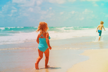 Fototapeta premium little girl and boy run play with waves on beach
