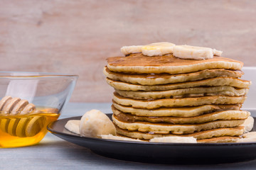 Delicious traditional American pancakes with banana slices and honey