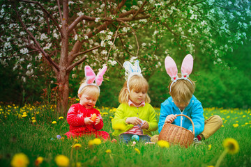 happy kids on easter eggs hunt in spring