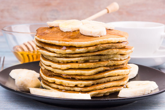 Delicious traditional American pancakes with banana slices and honey