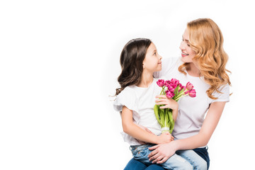 happy mother and little daughter with bouquet of flowers isolated on white, mothers day holiday concept