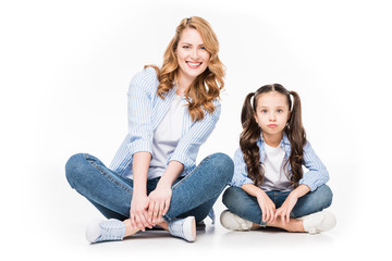 portrait of smiling mother and daughter in denim clothing looking at camera isolated on white