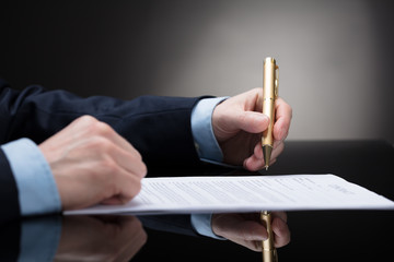 Businessperson Holding Pen To Sign On Contract Paper