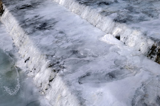 A completely frozen river weir in winter