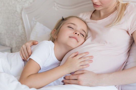 cheerful daughter listening pregnant mother belly