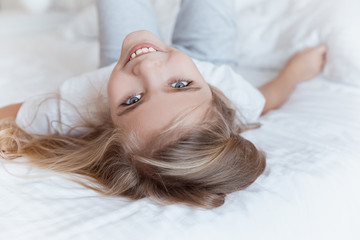 smiling kid lying on bed on back and looking at camera