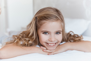 smiling kid lying on bed and looking at camera