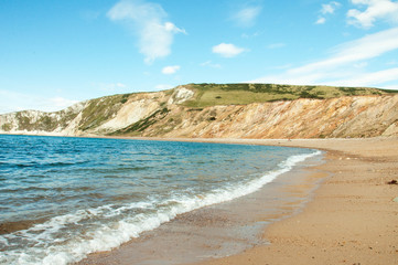 Fototapeta na wymiar Beautiful summertime beach and ocean waves along Tyneham beach in Dorset, England.