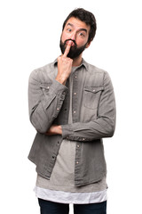 Fototapeta premium Handsome man with beard making horn gesture on white background