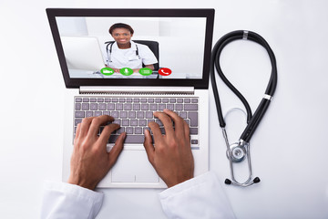 Doctor Video Conferencing With Colleague On Laptop
