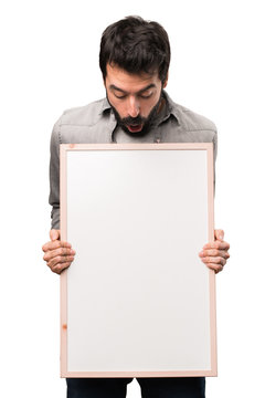 Handsome man with beard holding an empty placard on white background