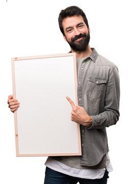 Handsome man with beard holding an empty placard on white background