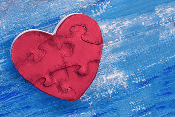 Valentine's day concept. Wooden heart puzzle of a red color on a blue wooden background