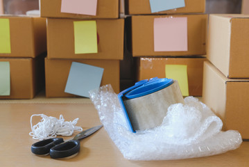 packing accessorie at workplace of startup small business owner. cardboard parcel box for online selling. entrepreneur seller desk. e-commerce, shipping concept