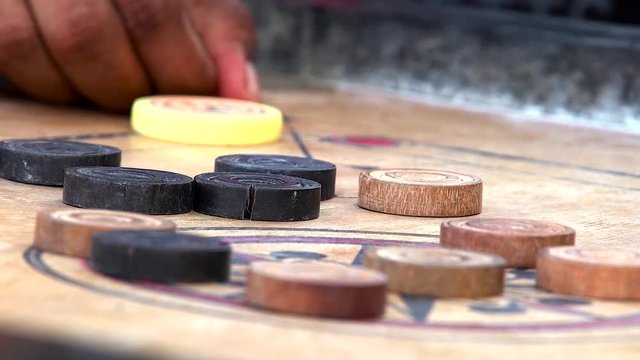 Closeup shot playing carom board games. Young boy wait and aim the shot.