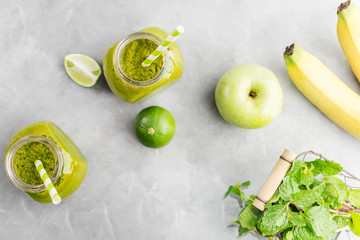 Green healty drink in mason jar with green apple, mint and lime on bright grey background. Vegetarian food concept. Detox. Text space