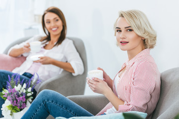selective focus of women with coffee cups spending time together