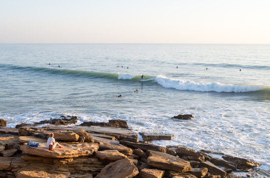 Surfer riding wave at panoramas in taghazout while two others paddle out.