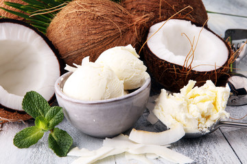 Bowl with balls of coconut ice cream and desiccated coconut on wooden table