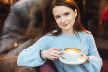 Portrait of girl hold coffee cup and look at camera. Stylish clothing wear. Autumn and winter weather. Blur background. Proffesional photo.