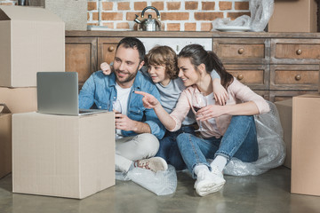 happy family using laptop while sitting in new house