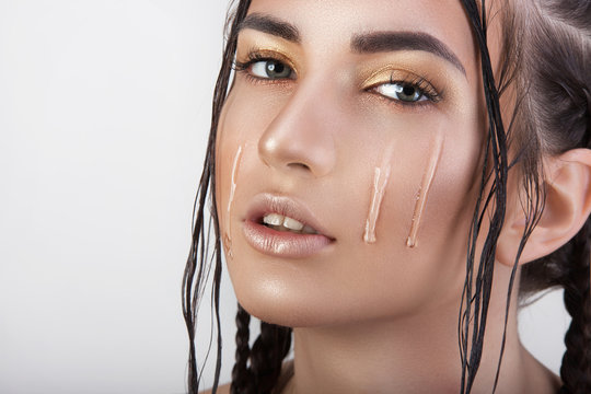 a girl with wet hair tears makeup on her face, clear liquid, drops flowing through the skin.
