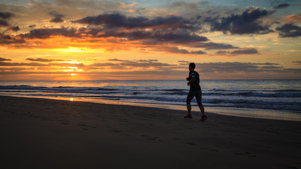 Woman is running by the beach at sunrise.