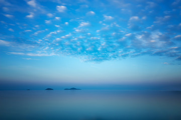 Sunrise blue ocean landscape with islands and reflections