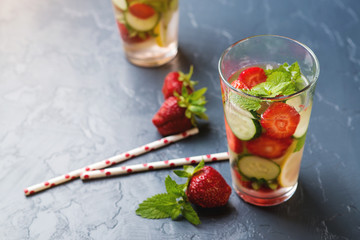 Detox water with strawberry and cucumber in glass on black background. Copy space.