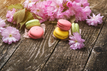 Pink sakura flowers with delisious macarons on dark wooden background , copy space, selective focus.