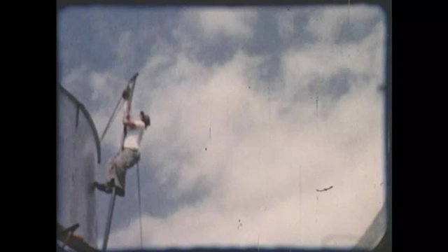 1950s era home movie clip of construction working climbing a pole