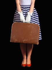 Girl in retro style holds suitcase on black background
