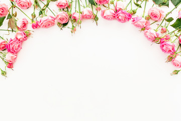 Floral frame made of pink roses on white background. Flat lay, Top view.