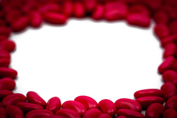 Selective focus of red kidney shape sugar coated tablet pills on white background with copy space