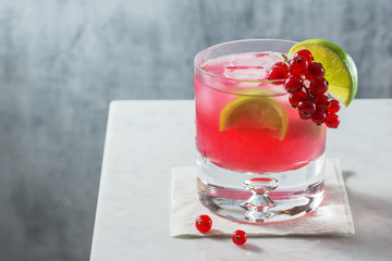 Red Currant Caipirinha Cocktail with Lime in Rocks Glass on Marble Counter