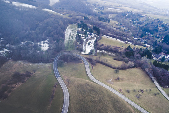 Aerial Top View Of Winter Forest And Winding Countryside road with a little bit of snow
