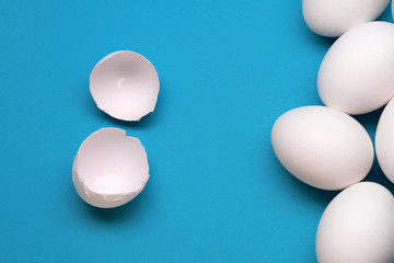 White Broken Egg Near The Whole Eggs On Blue Background