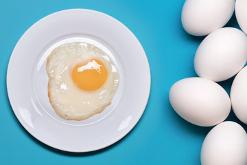 Fried Eggs In A White Plate Near Eggs On A Blue Background